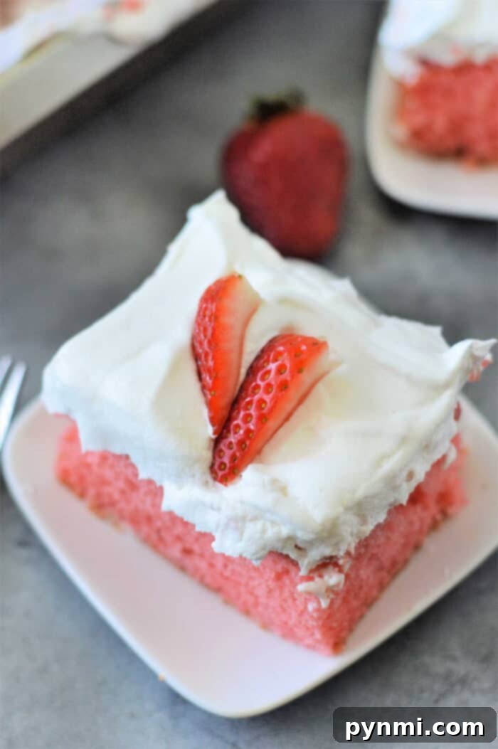 Entire strawberry cake mix poke cake on a serving platter, beautifully garnished with whipped cream and fresh strawberries, ready for a gathering.