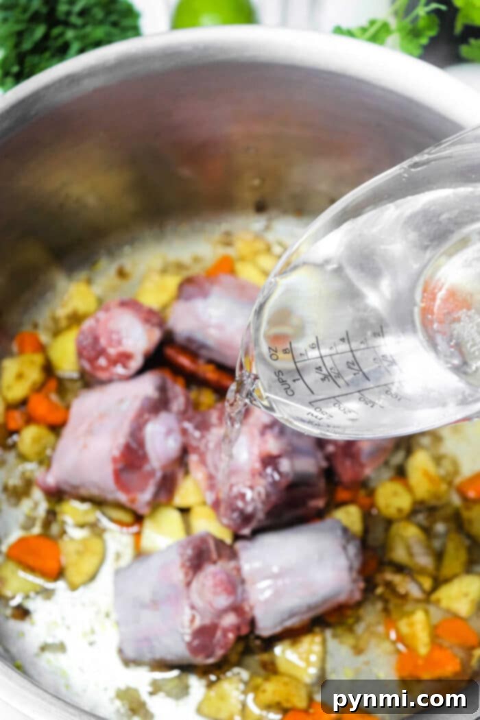 Pho Broth Recipe - A large pot filled with rich, simmering pho broth with beef bones and aromatic spices visible.