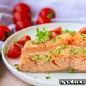 Salmon garnished with fresh herbs graces a white plate, evoking the subtle aroma of boiled fish, while cherry tomatoes add a pop of color in the background.