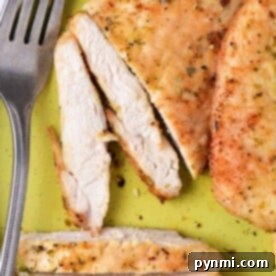 Thinly sliced chicken breast, perfectly tender, elegantly rests on a green plate beside a fork. Cooked to perfection in the air fryer at 375 degrees, each bite promises a delicious experience.