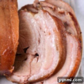 Sliced roasted pork shoulder on a white plate, showing crispy skin and juicy, tender meat—perfect inspiration if youre wondering how long to cook pork shoulder at 350 for similar delicious results.