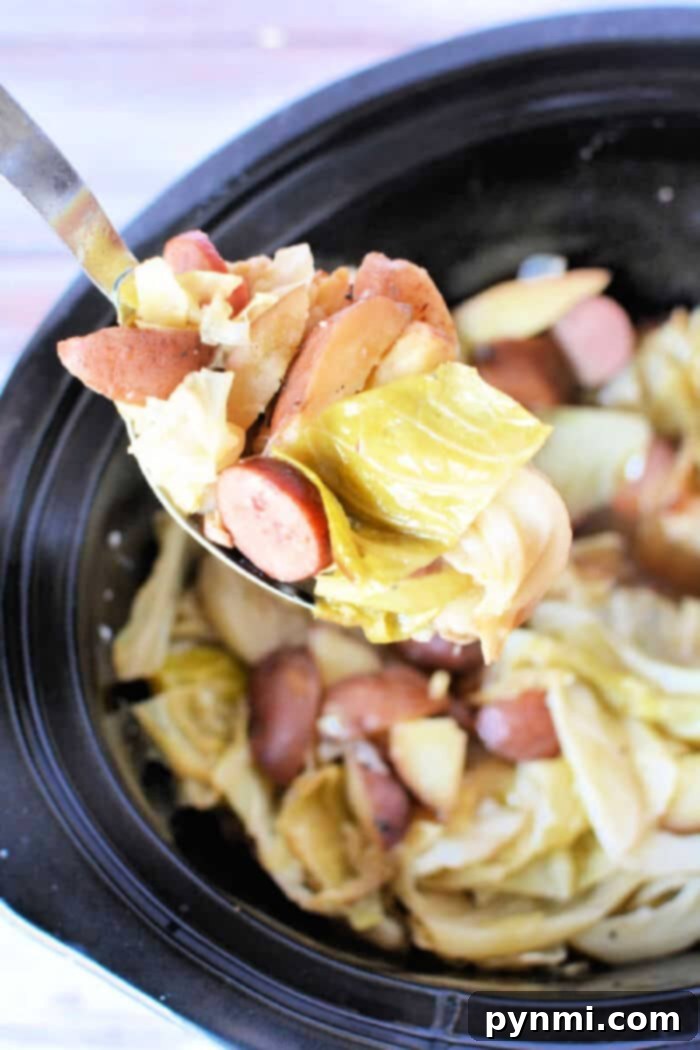 A ladle scoops a generous portion of sliced sausages, tender cabbage, and chunky potatoes from a crockpot, showcasing a delightful and comforting slow cooker stew or casserole.