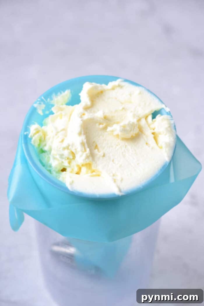 Homemade frosting in a blue churn with cream residue on top, resembling the rich texture of a Lemon Curd Cake, set against a light background.