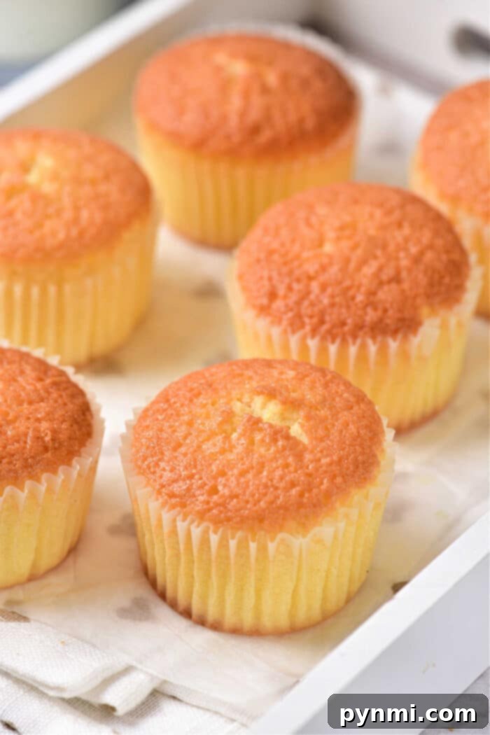 Sunshine Lemon Muffins 6 Two lemon curd muffins, one unwrapped, on a rustic wooden board