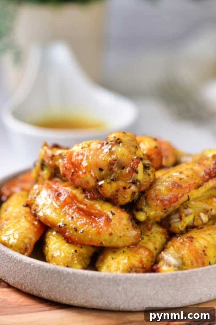 A tantalizing plate of hot honey lemon pepper wings, garnished with fresh herbs and lemon slices, ready to be enjoyed.