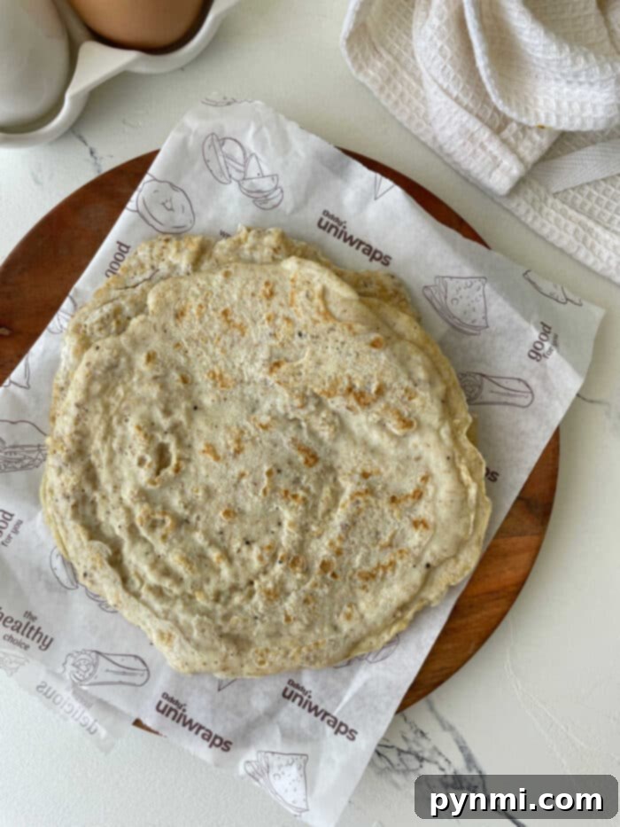 A pair of egg white tortillas, one neatly folded with visible golden brown edges, the other flat and perfectly round, poised for various fillings.