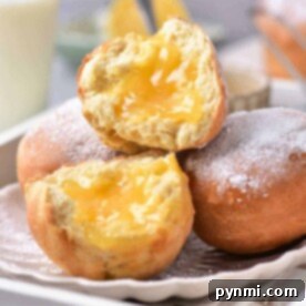 Sunshine Lemon Donuts 8 Close-up of air fryer lemon-filled donuts dusted with powdered sugar on a plate, with a glass of milk in the background.