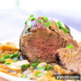 Sliced eye of round roast perfectly prepared garnished with herbs and served alongside sautéed mushrooms and onions.