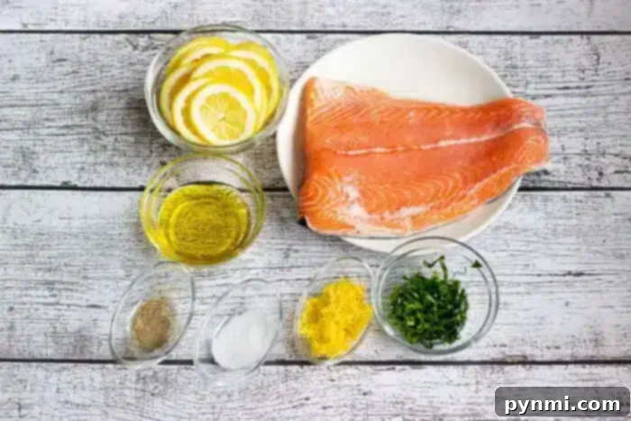 Optimal Salmon Baking Time 350 3 A plate with a raw salmon fillets is surrounded by small bowls containing lemon slices, olive oil, black pepper, salt, lemon zest, and chopped herbs, all placed on a white wooden surface.