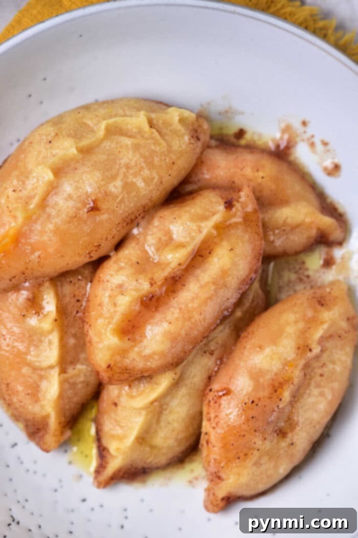 Golden Sweet Potato Dumplings 2 Golden-brown sweet potato dumplings drizzled with a sweet glaze, served on a white plate.