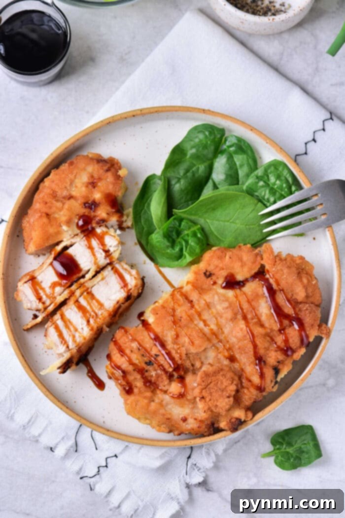 Tenderized Pork Cutlets 6 Fried pork cube steak drizzled with barbecue sauce rest alongside fresh spinach and a fork on a plate.