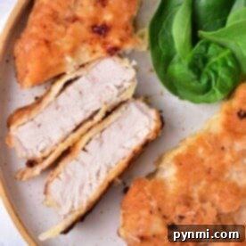 Close-up of succulent pork cube steak fried to perfection, served on a plate with fresh spinach leaves.