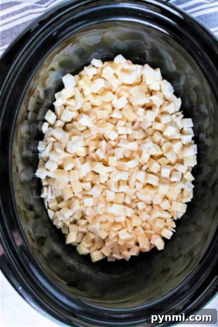 Diced frozen potatoes inside a slow cooker on a striped cloth backdrop, showing their versatility for slow-cooked dishes.