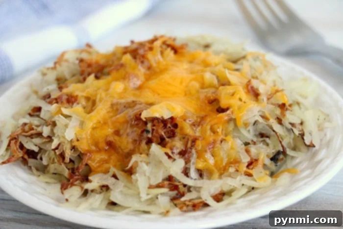 A plate of cheesy air fryer hash browns rests invitingly on a white table, ready to be served.