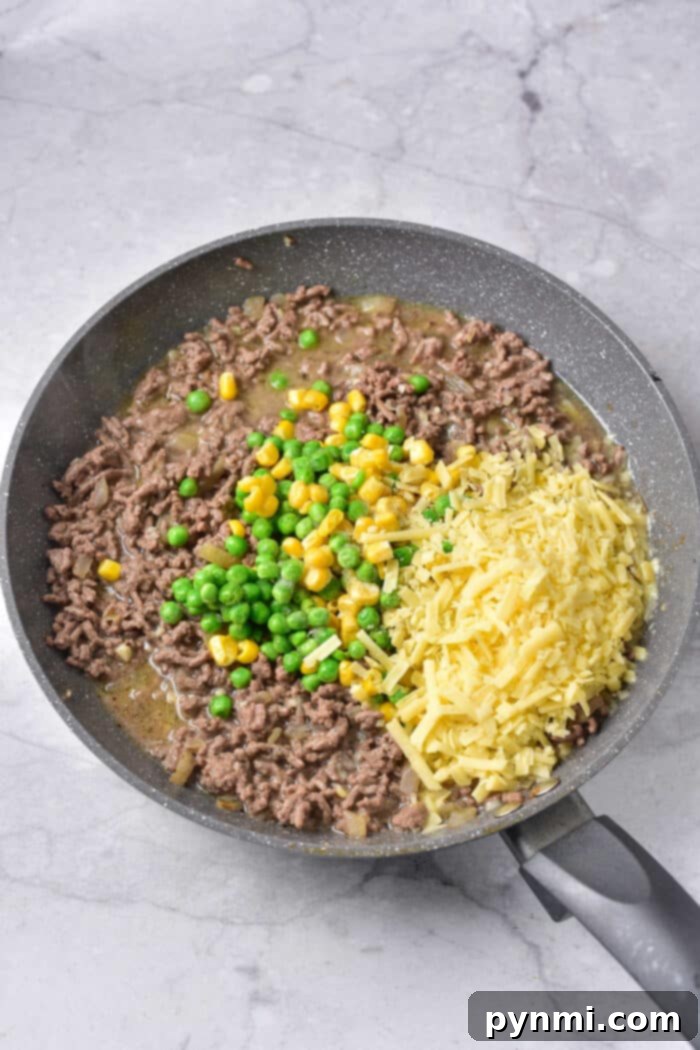 Hearty Beef and Hash Brown Bake 3 Close-up of a bubbling casserole with shredded potatoes, meat, and melted cheese