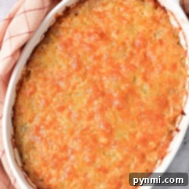 Golden-brown Ground Beef Hash Brown casserole in a white dish on a plaid cloth.
