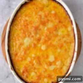 Dairy-free scalloped potatoes lie golden-brown in an oval casserole on a marble surface.
