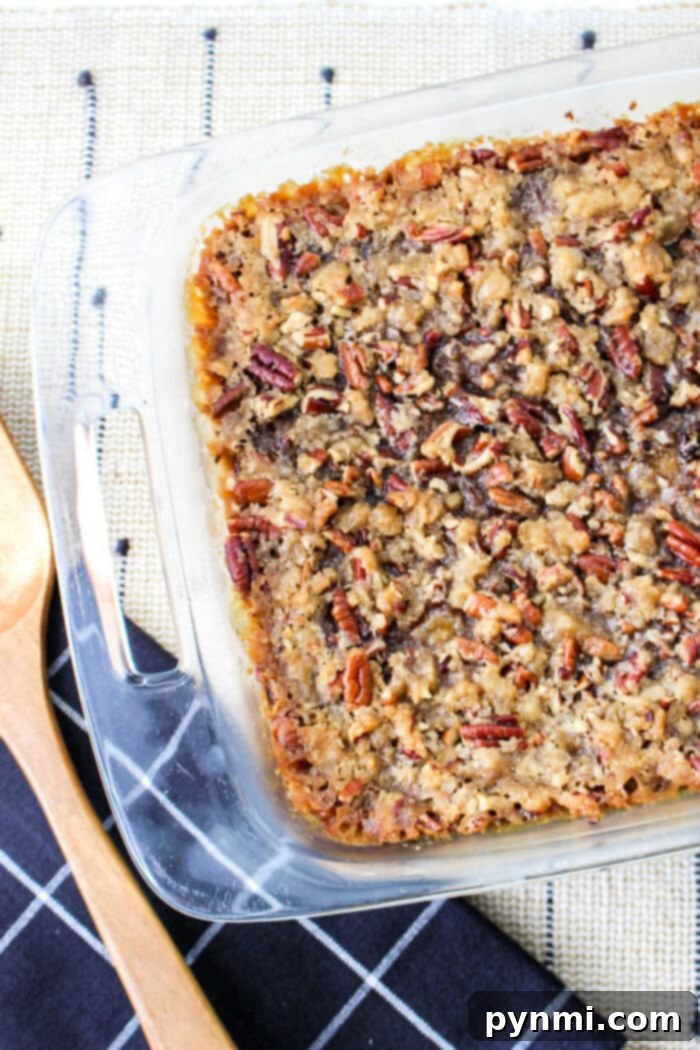 A glass baking dish with a freshly baked sweet potato casserole with canned yams, accompanied by rustic wooden cooking utensils.
