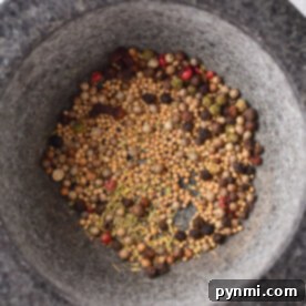A variety of whole spices in a stone mortar, perfect for crafting your own corned beef spice recipe.