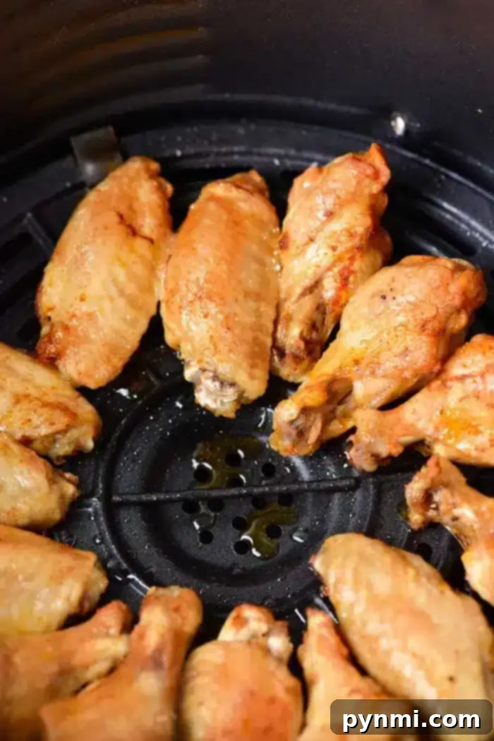Poached Chicken Wings 5 Golden-brown chicken wings, reminiscent of their tender boiled counterparts, are arranged in a circle inside an air fryer basket.