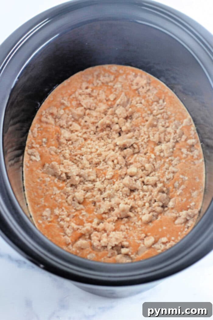 Slow Cooker Pumpkin Perfection 5 Pumpkin Crockpot Dump Cake, showcasing a large portion ready to be served from the slow cooker.