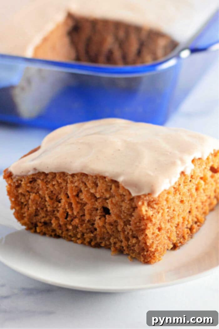 Golden Pumpkin Delight 2 A slice of frosted pumpkin cake, reminiscent of a classic Crazy Cake, rests on a white plate with a vibrant blue dish in the background. This homemade pumpkin dessert is dairy-free and perfect for Fall.