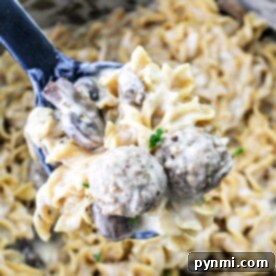 Spoon scooping creamy Meatball Stroganoff pasta with tender mushrooms from a pot.