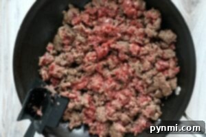 Ultimate Big Mac Bake 6 Ground beef being browned in a black skillet with a black spatula resting on the side—perfect for an easy sloppy joe recipe 3 ingredients or less.