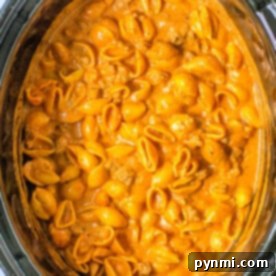A Crock-pot filled with creamy pasta shells in a rich tomato sauce delivers the comforting essence of a classic goulash.