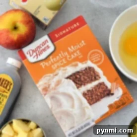 Quick Cake Mix Apple Delight 6 An array of tempting ingredients awaits on the kitchen counter: a box for Apple Cake with Cake Mix, creamy pudding, aromatic cinnamon, chopped apples, an egg, golden syrup, and a trusty measuring cup to tie it all together.