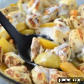 A skillet of cinnamon rolls with peaches and cream, served with a black spoon, offers a delightful twist reminiscent of a cinnamon roll peach cobbler.
