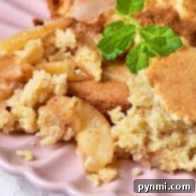 Close-up of a delectable apple crumble with ice cream on a pink plate, reminiscent of a pear upside down cake, garnished with a fresh sprig of mint.