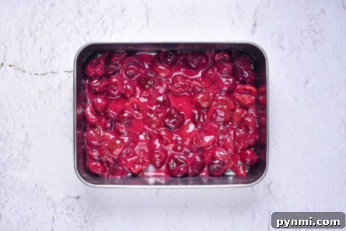 Simple Homemade Cherry Cobbler 4 Cobbler with canned cherries baking in a dish, showing bubbling fruit and golden crust
