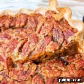 Close-up of a pecan pie with a slice being lifted, revealing its flaky crust and nutty, caramelized filling. This delightful treat brings to mind an easy pumpkin pie with pecan topping—a fusion of flavors perfect for any festive occasion.