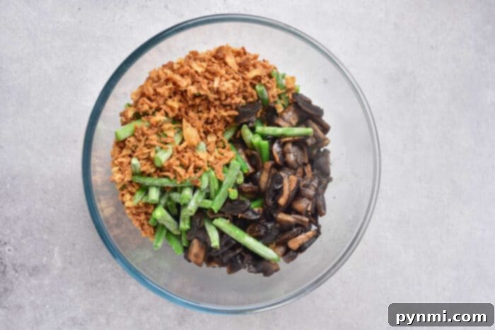 cheesy green bean casserole with frozen green beans baking in a dish, showing melted cheese and crispy onions.