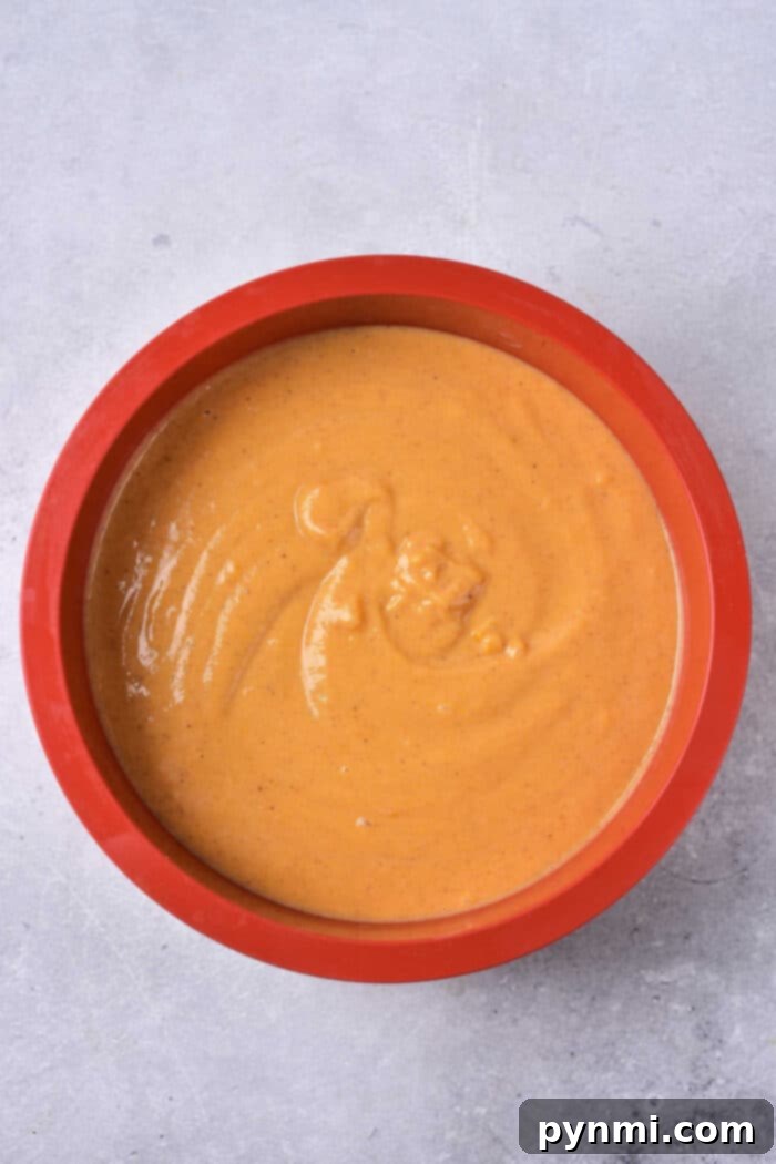 Pumpkin Pie Without a Crust, showing a slice removed, revealing the creamy texture, topped with whipped cream.