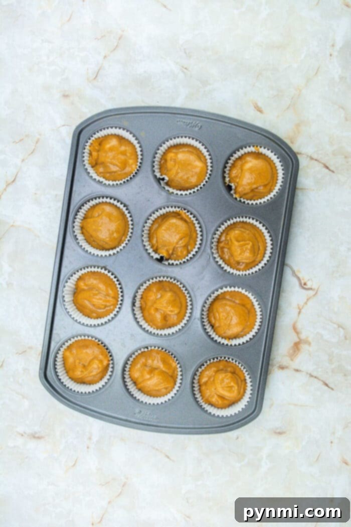 A batch of freshly baked pumpkin cupcakes cooling on a wire rack, ready for frosting