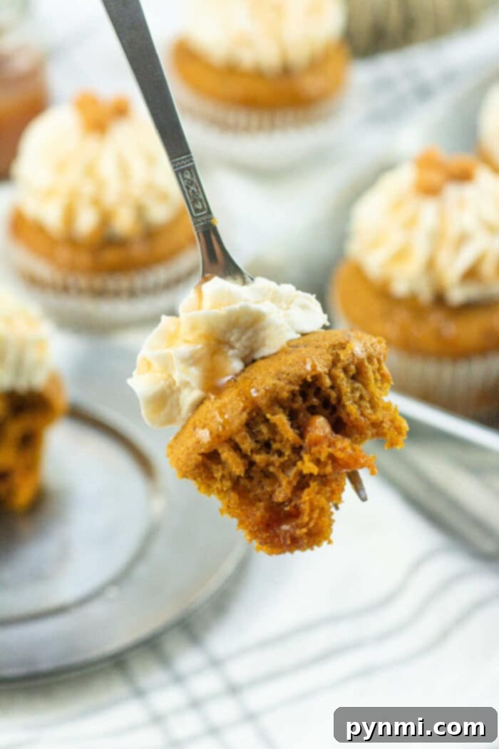 Beautifully frosted pumpkin cupcakes with piped cream cheese frosting, garnished with a sprinkle of spice