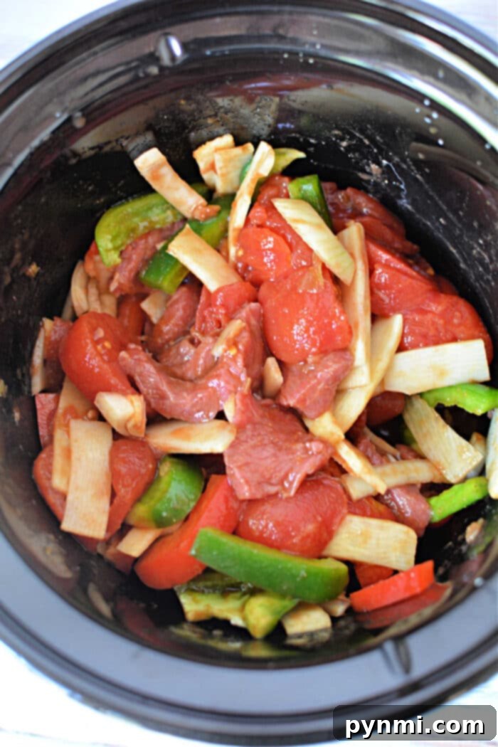 A bowl of Slow Cooker Pepper Steak served with white rice and green onions