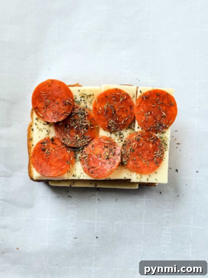 Close-up view of golden pizza on toast with pepperoni and melted cheese, garnished with fresh basil.