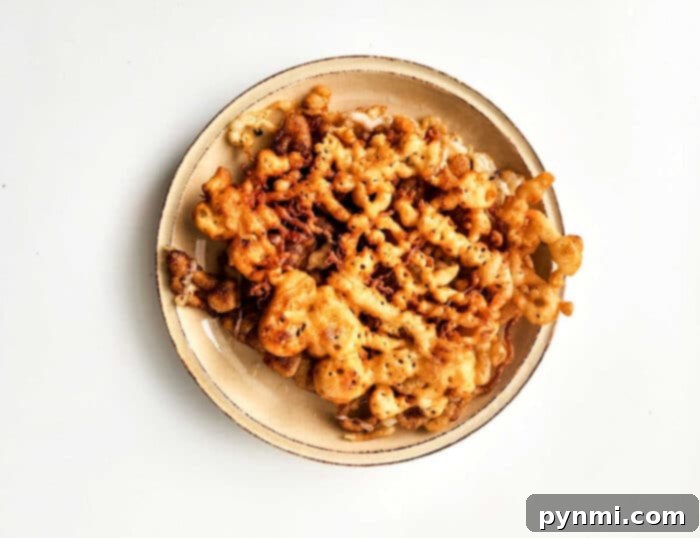 easy funnel cake recipe - A plate with a homemade funnel cake, generously topped with powdered sugar, ready to be enjoyed as a simple and delicious dessert.