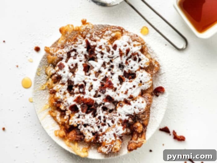 Funnel Cake without Eggs - A close-up of a perfectly fried, egg-free funnel cake, showcasing its golden color and intricate lacy pattern.