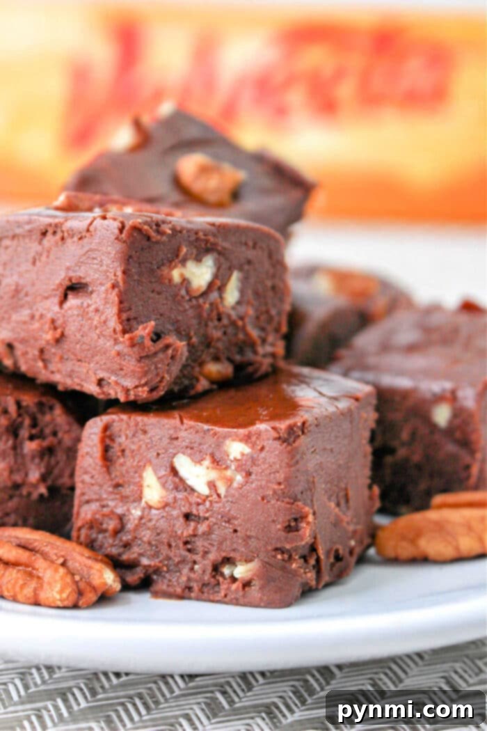 Surprisingly Velvety Fudge 2 Close-up of decadent chocolate Velveeta fudge with pecan pieces stacked on a plate, highlighting its smooth texture.