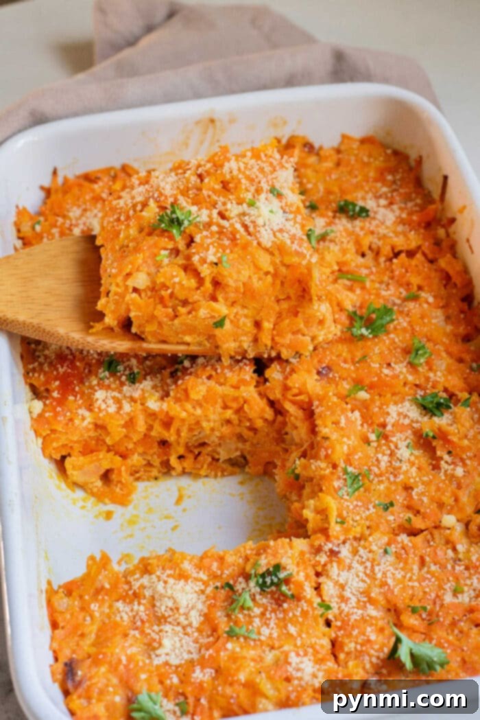 Grandma's Sweet Carrot Bake 6 Cheesy carrot casserole in a white baking dish, topped with parsley, with a wooden spatula serving a piece.