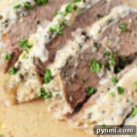 Effortless Slow Cooker London Broil 7 Enjoy tender London Broil for the Slow Cooker, featuring sliced beef topped with a creamy sauce and garnished with chopped parsley.
