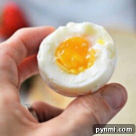 A hand delicately cradles a hard-boiled egg, its runny yolk glistening like it was just perfected in a toaster oven.