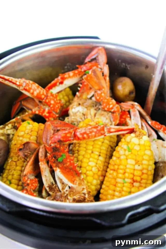 A metal pot filled with cooked crabs, corn on the cob, and potatoes.
