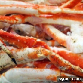 A pile of frozen red and white crab legs rests on ice, perfect for anyone curious about how to cook frozen crab legs to perfection.