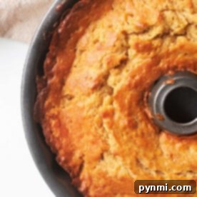 A freshly baked bundt cake in a round pan on a light surface beckons with its golden crust, much like knowing how to tell if banana bread is done—by ensuring it's perfectly baked throughout.