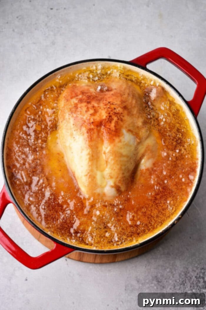 Fried Chicken's Perfect Fry: Optimal Oil Temperature 3 A pot with a large piece of meat simmers in oil, its red handles standing out. Curious about perfect fried chicken? Ensure your oil is hot enough—an essential tip when crafting flavorful dishes like this.
